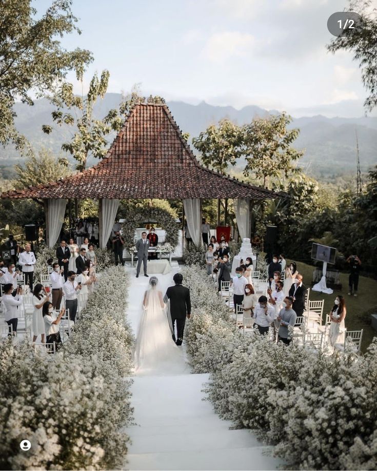 a bride and groom walking down the aisle to their wedding ceremony in front of an outdoor gazebo