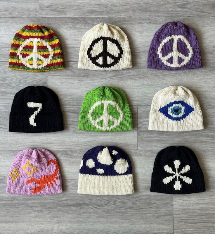 six knit beanies with peace symbols on them, all in different colors and sizes