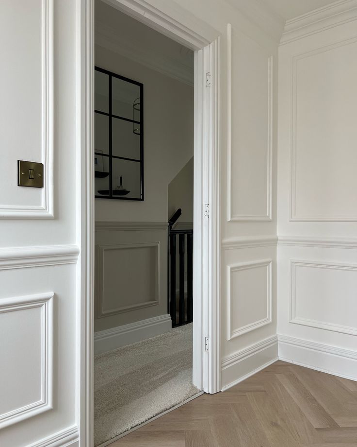 an empty room with white walls and wood flooring is seen from the doorway to the hallway