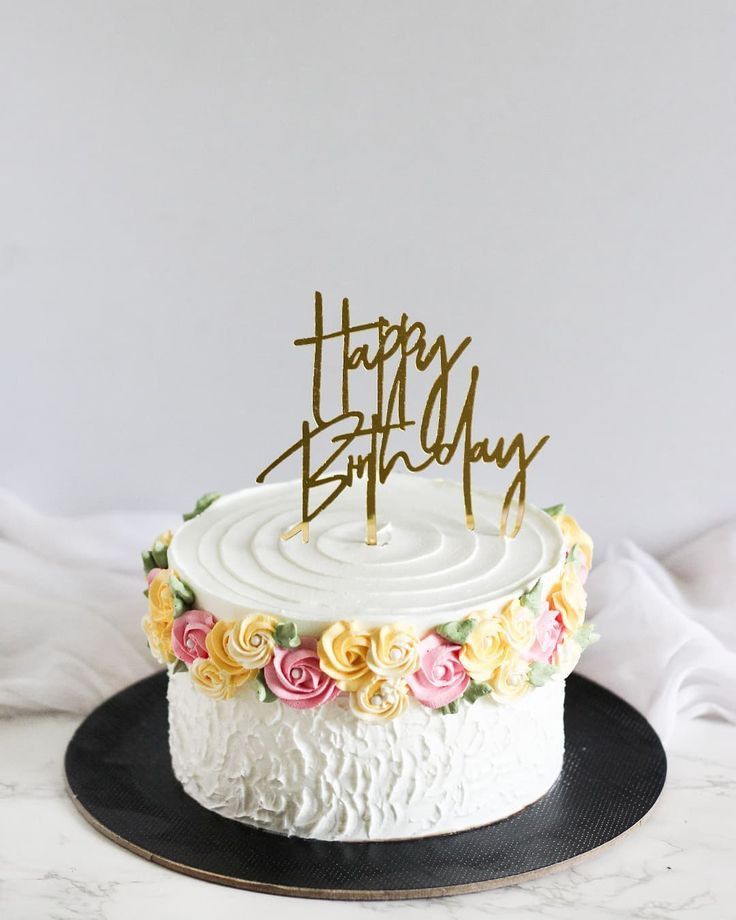 a birthday cake with white frosting and colorful flowers on the top that says happy birthday