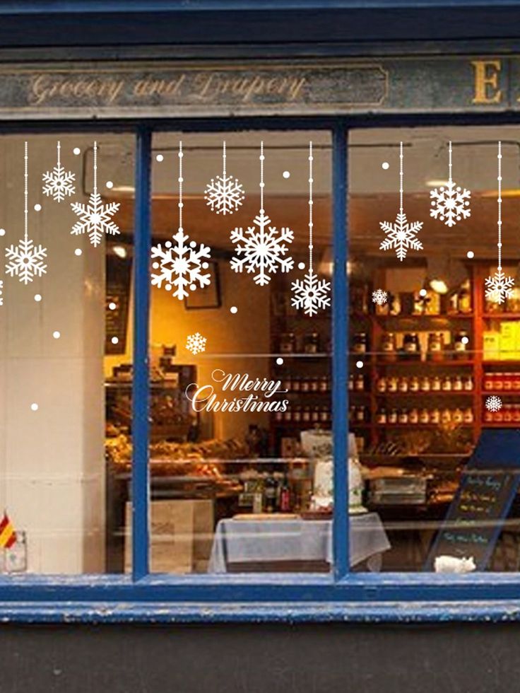 a store front with snowflakes hanging from the windows and decorations on the window