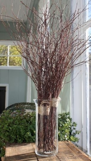 a vase filled with branches sitting on top of a wooden table