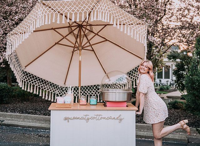 a woman standing next to an umbrella selling food