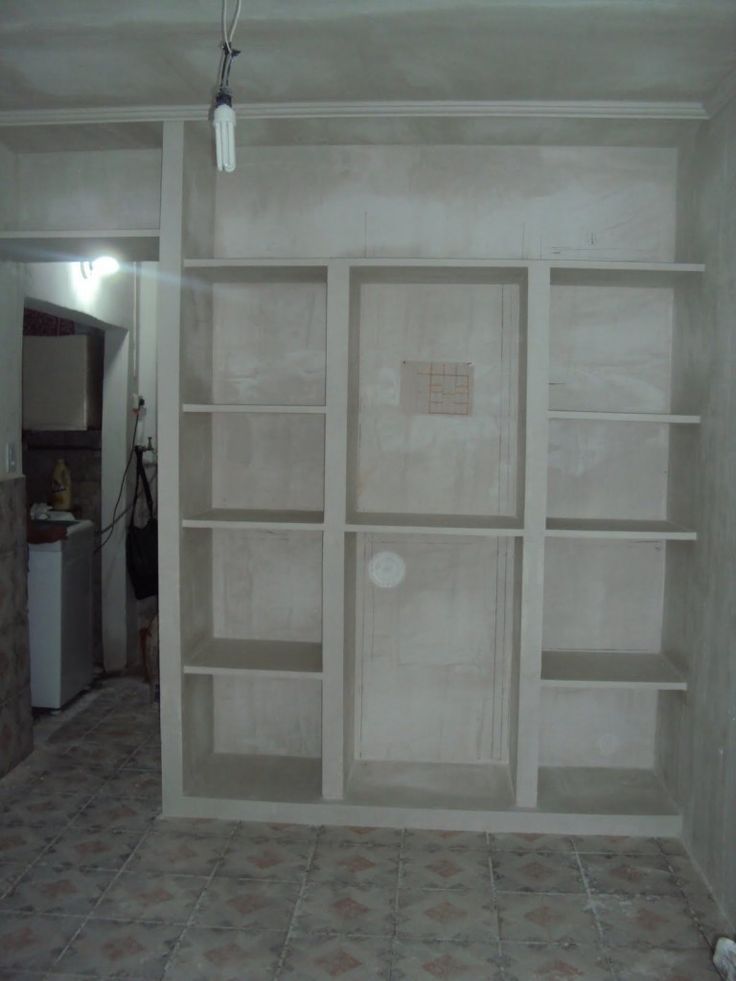 an empty room with white shelves and tile flooring