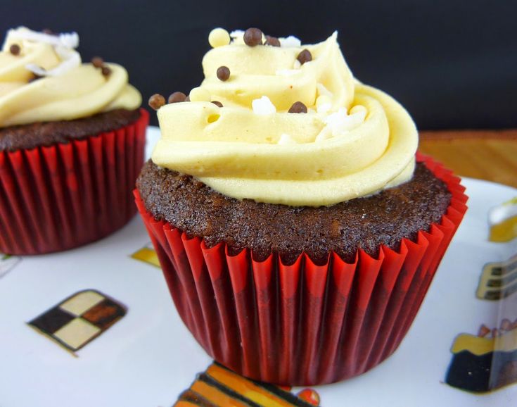 two chocolate cupcakes with white frosting and sprinkles on top