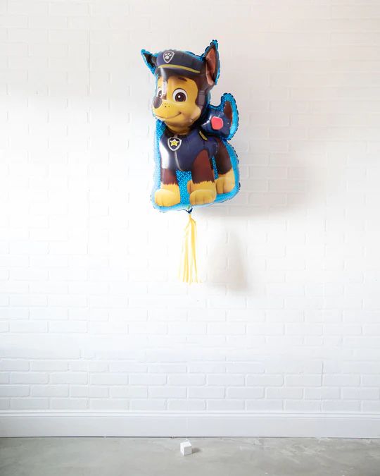 a balloon shaped like a dog with a hat on it's head hanging from the wall