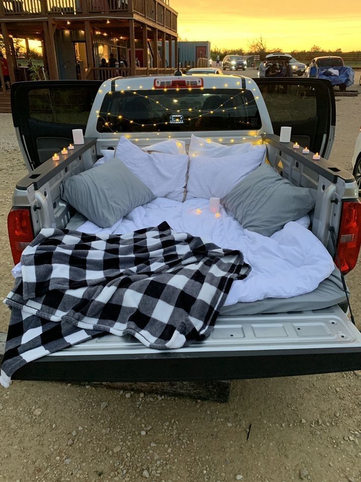 the back end of a pick up truck with pillows and blankets on it's bed