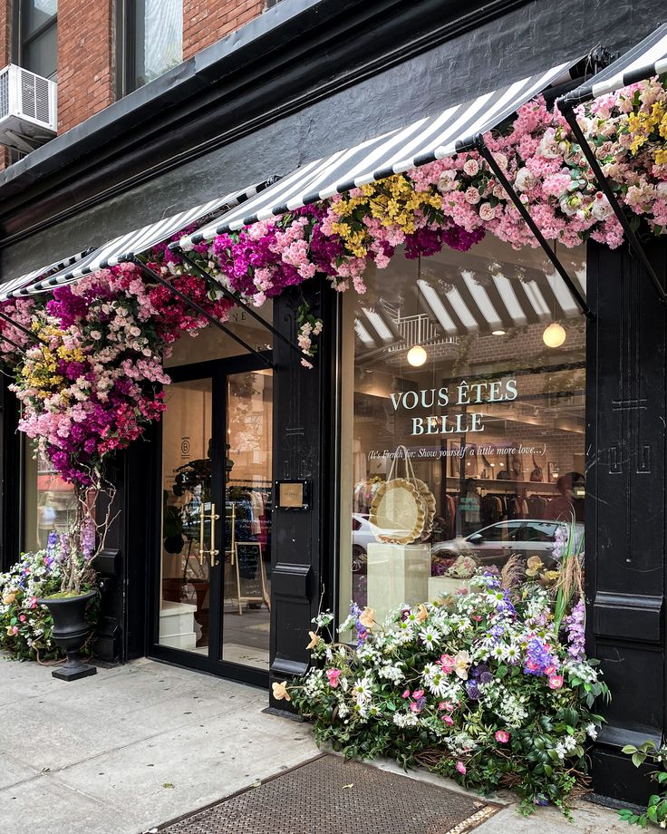 a store front with flowers hanging from the windows