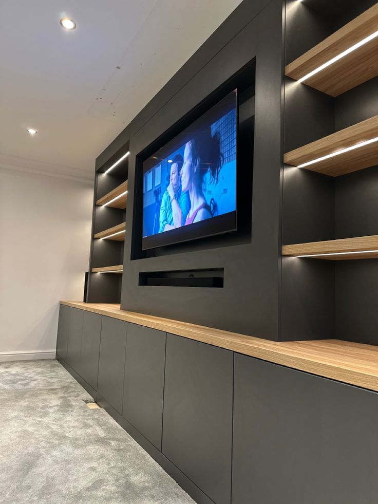 a flat screen tv mounted to the side of a wall in a room with shelves