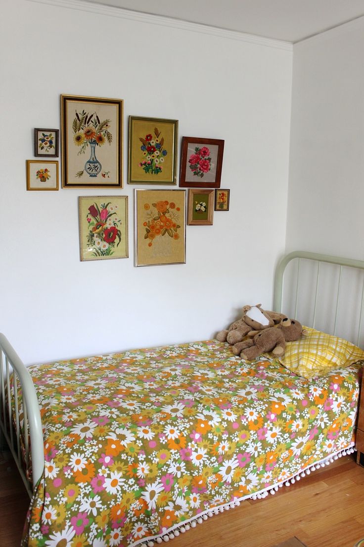 a bed with a floral bedspread and pictures on the wall next to it