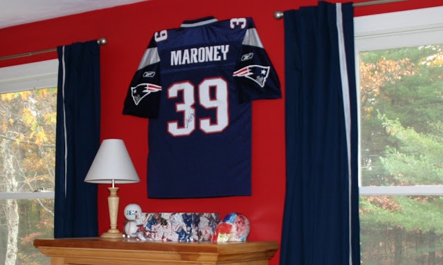 a football jersey hanging on the wall in a room with red walls and blue drapes