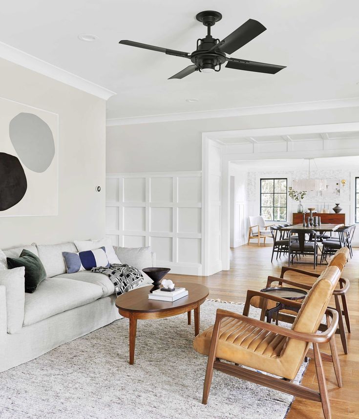 a living room filled with furniture and a ceiling fan in the middle of it's wall