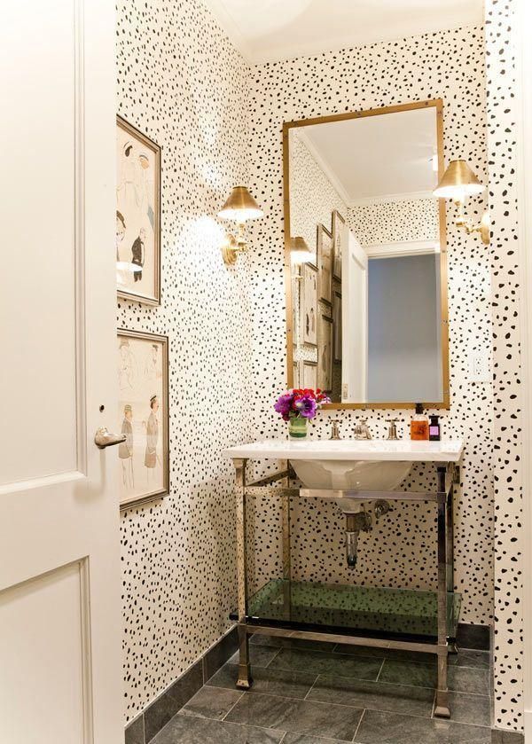 a white sink sitting under a bathroom mirror next to a wall covered in black and white dots