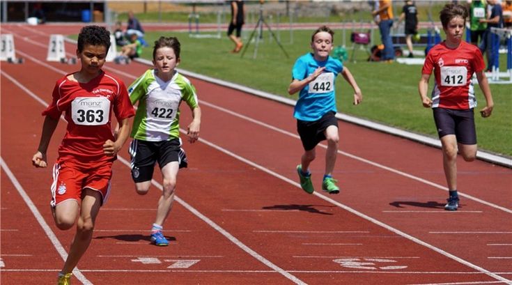 three boys running on a track in the middle of two other boys and one girl