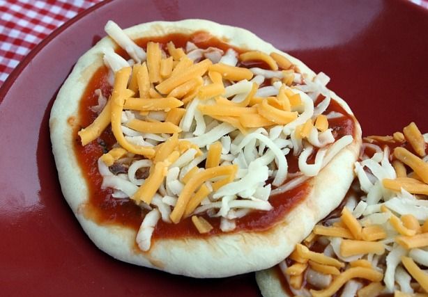 two small pizzas with cheese and sauce on them are sitting on a red plate