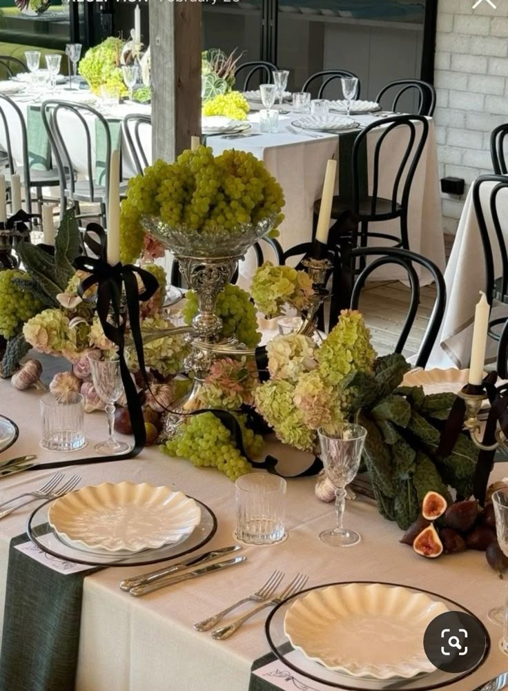 the table is set with plates, silverware and green centerpieces on it