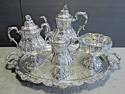 an ornate silver plate with four pieces on it and two serving trays in the middle