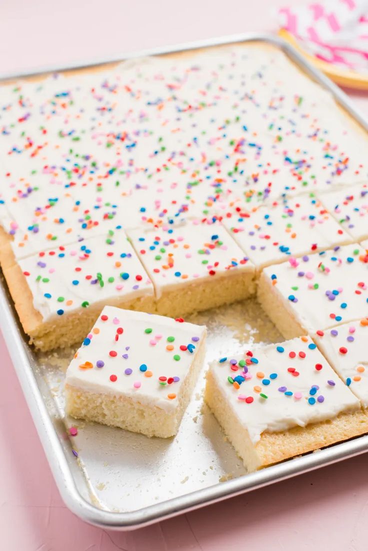 several pieces of cake on a tray with sprinkles and white frosting