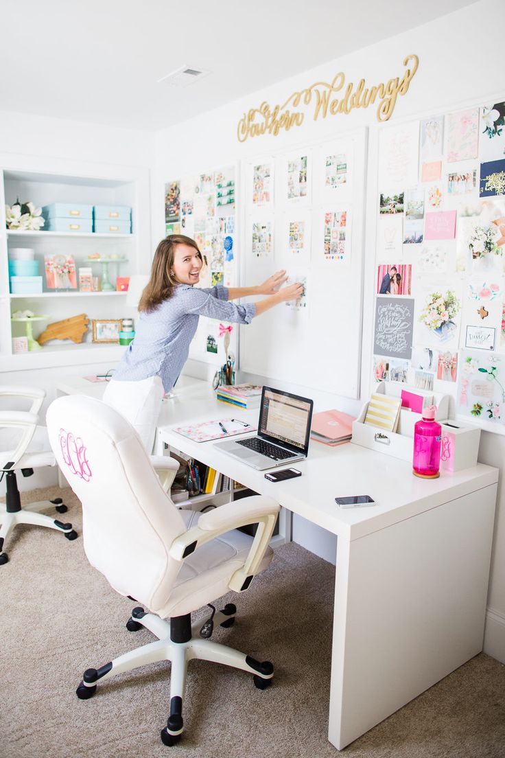 a woman standing in front of a desk with a laptop