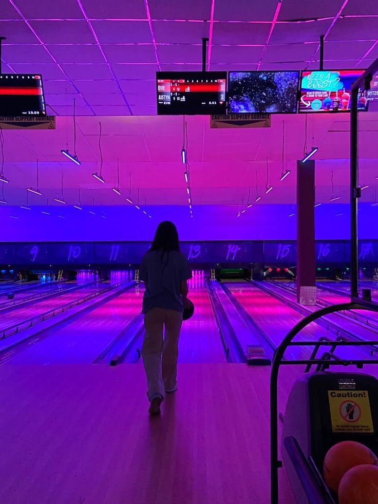 a woman is walking down the bowling alley