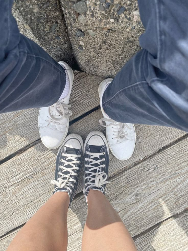 two people standing next to each other on top of a wooden floor with their feet in the air