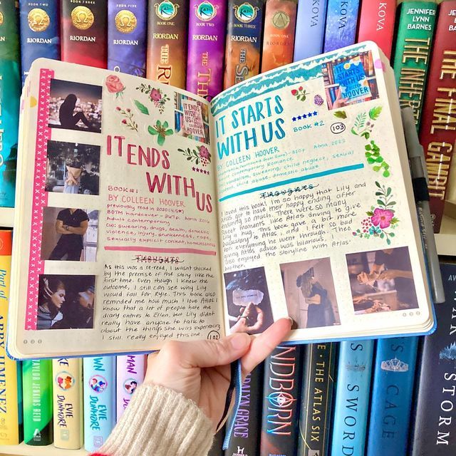 a person is holding an open book in front of a shelf full of colorful books