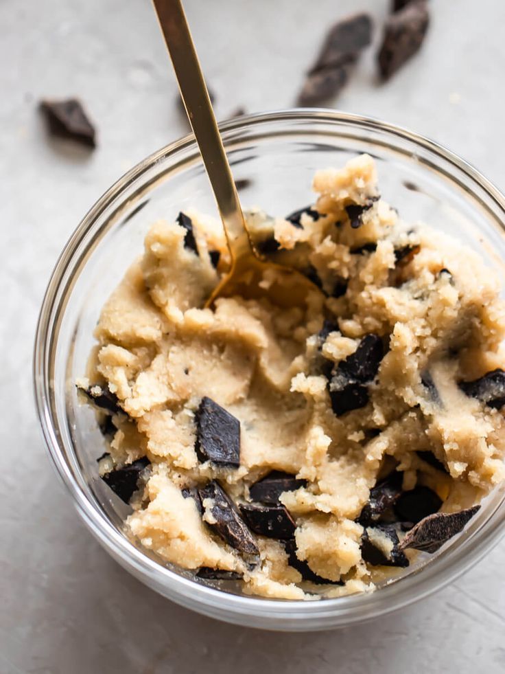 a glass bowl filled with ice cream and chocolate chips on top of a white surface