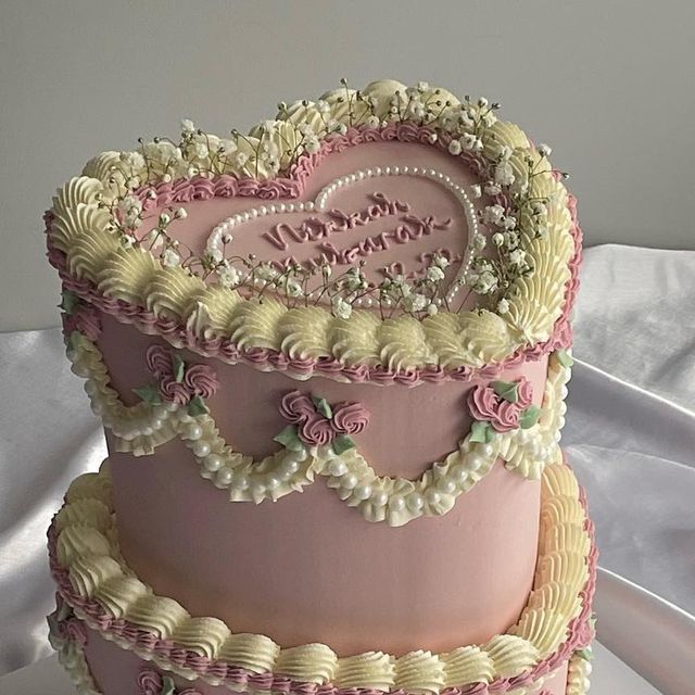 a three tiered cake with pink frosting and white icing, decorated with flowers