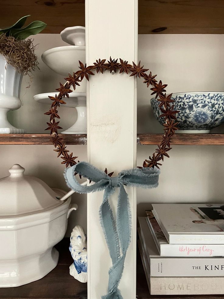 a wreath is hanging on the side of a book shelf next to other books and vases