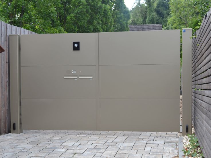 a gated in area with brick pavers and wooden fence surrounding it, surrounded by trees