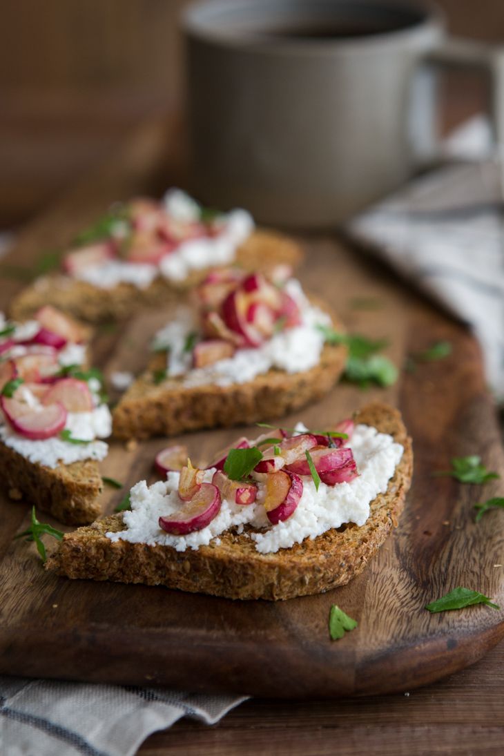 toasted bread topped with goat cheese and radishes on a wooden cutting board