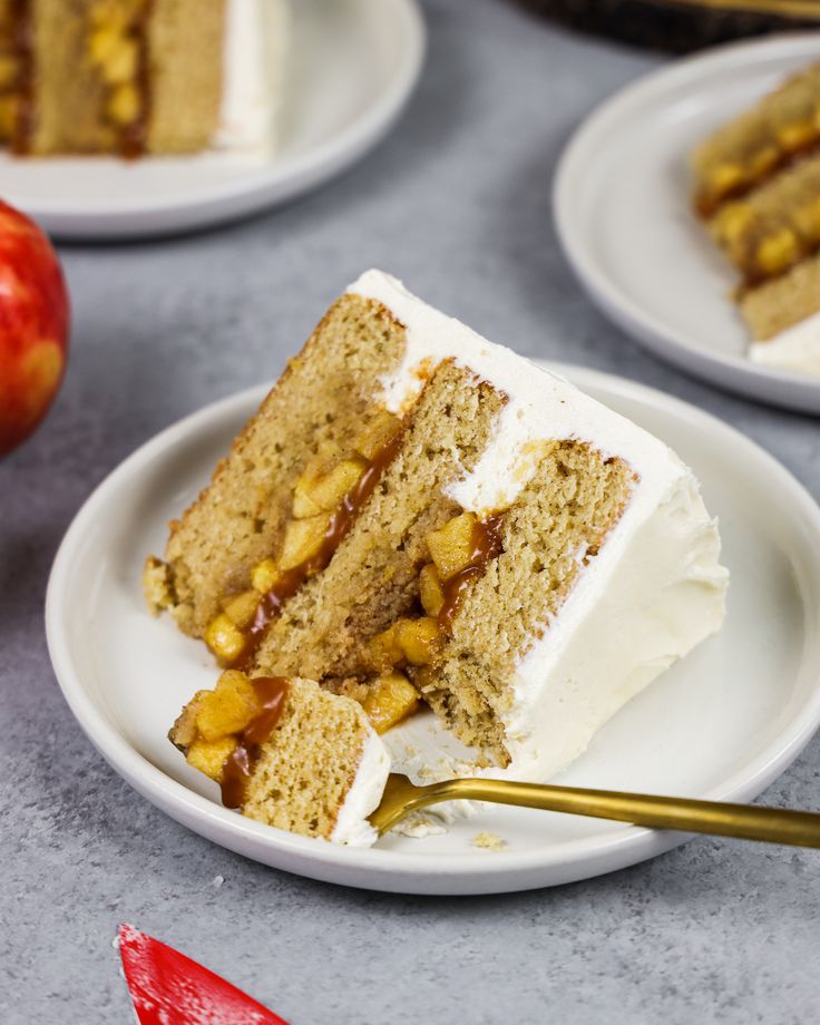 several slices of cake on plates with apples in the background and one slice being eaten