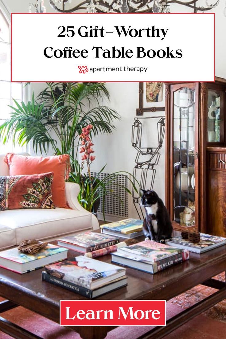 a coffee table with books on it and a cat sitting in front of the table