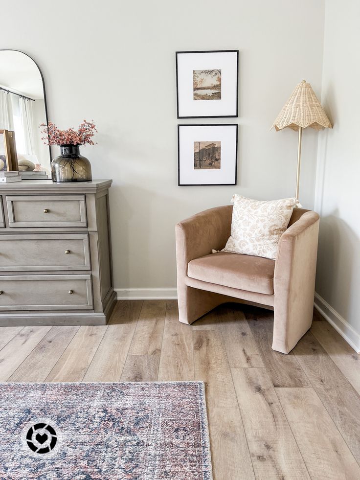 a living room with a chair, dresser and rug on the wooden floor in front of it