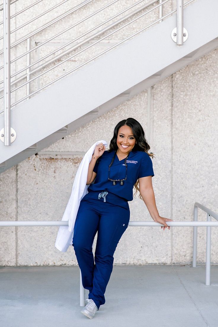 a woman in blue scrubs is posing for the camera