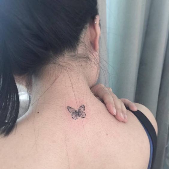 a woman with a small butterfly tattoo on her back neck and upper part of the neck