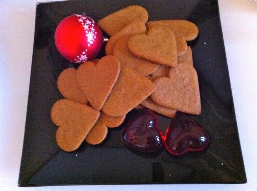 some heart shaped cookies are on a black plate with sunglasses and a red ornament