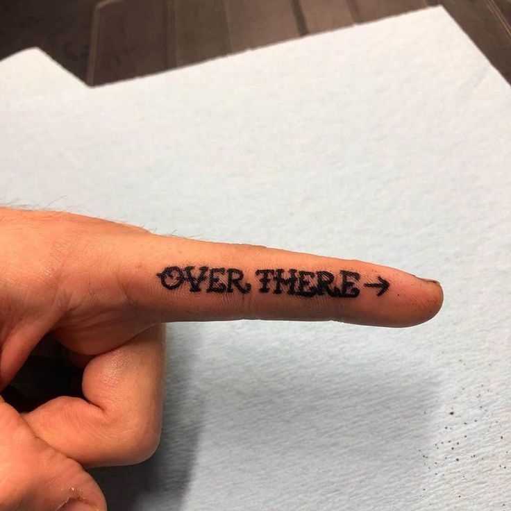 a person's finger with the word over there written on it in cursive font