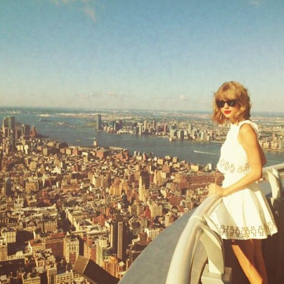 a woman standing on top of a tall building in front of a cityscape