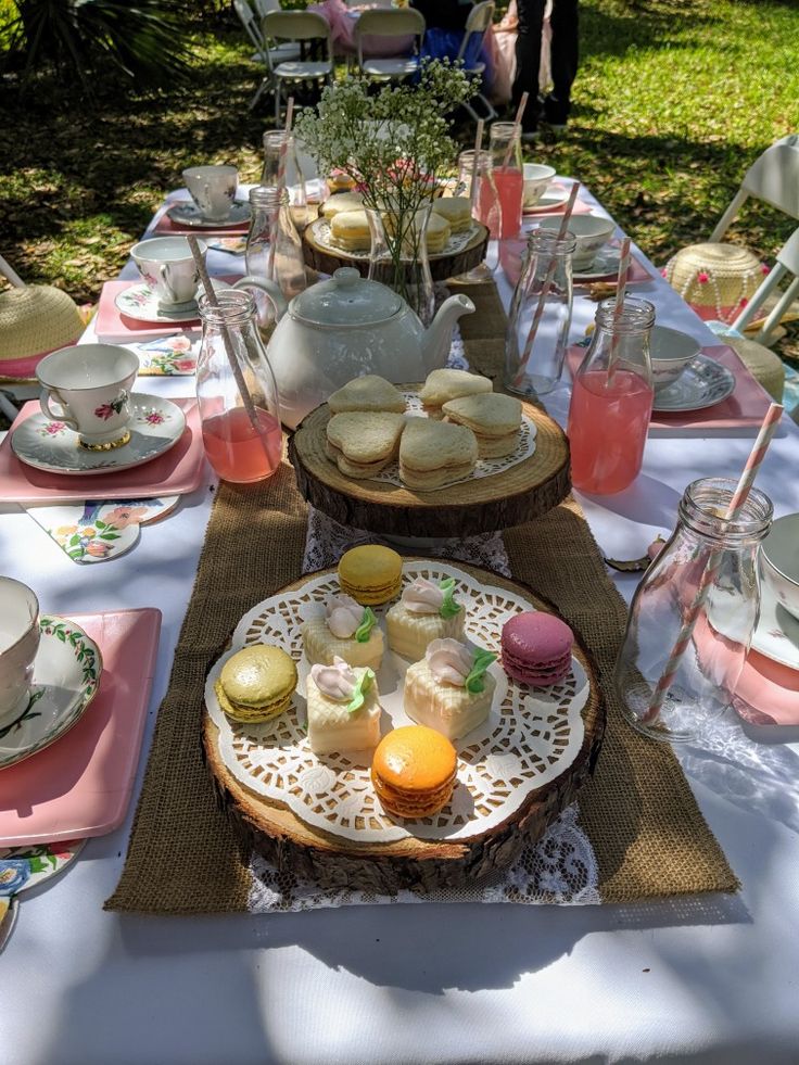 a table set up with plates, cups and saucers for afternoon tea party in the garden