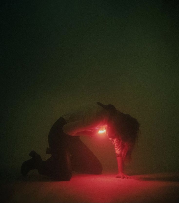 a man kneeling down next to a woman with a red light in her hand on the ground