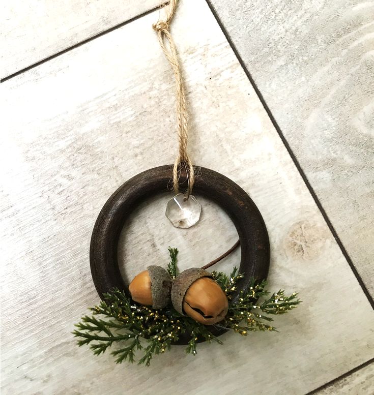 a wreath with acorns and pine cones hanging from a rope on the floor