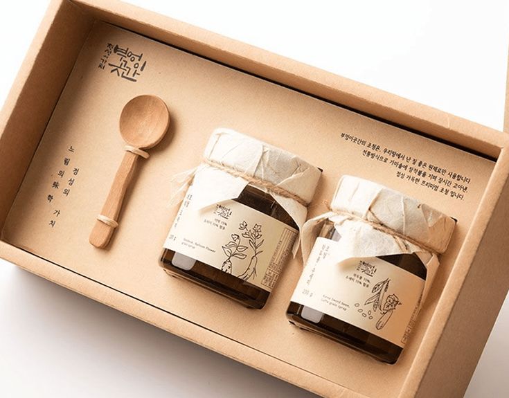 two bottles of honey in a box with spoons