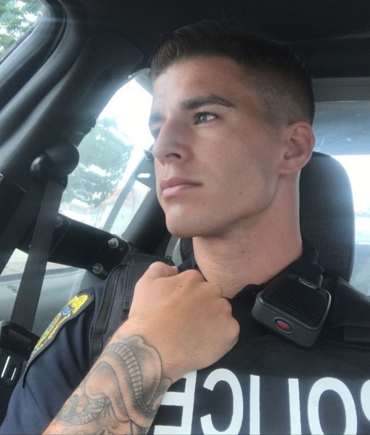 a police officer sitting in the back seat of a car with tattoos on his arm