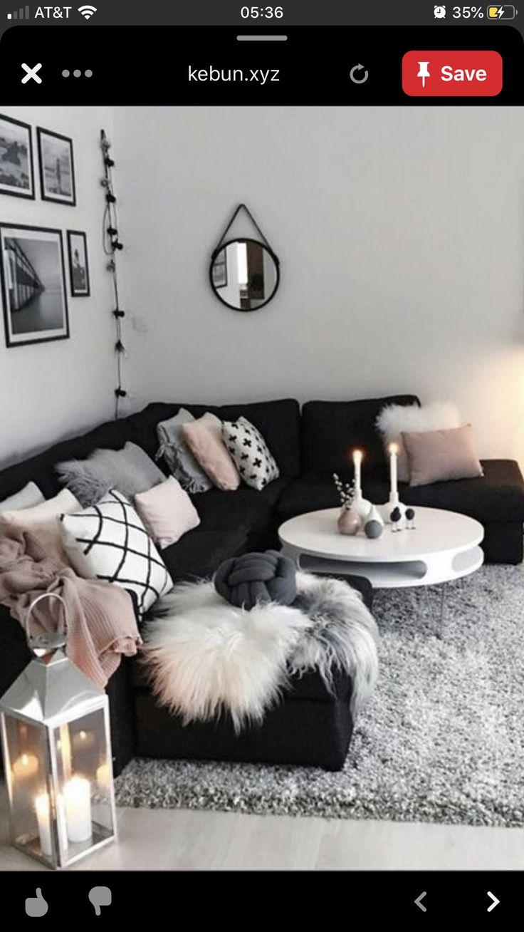 a living room filled with black furniture and lots of white pillows on top of it