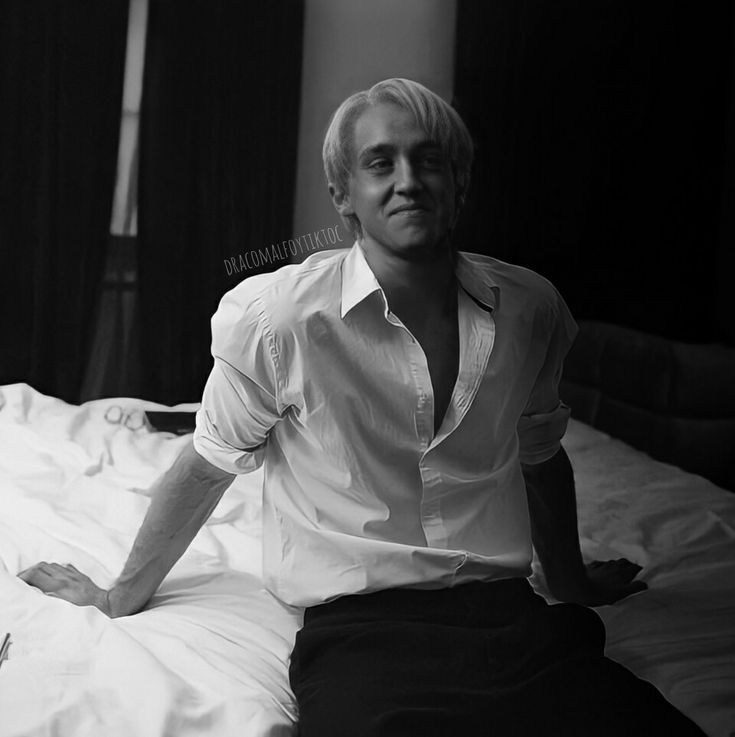 a man sitting on top of a bed in a white shirt