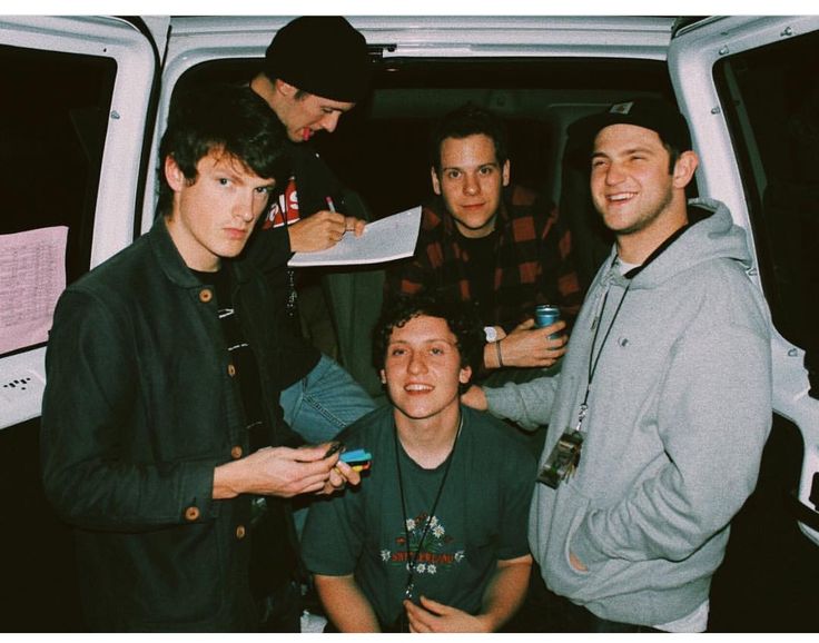 four young men standing in front of a van