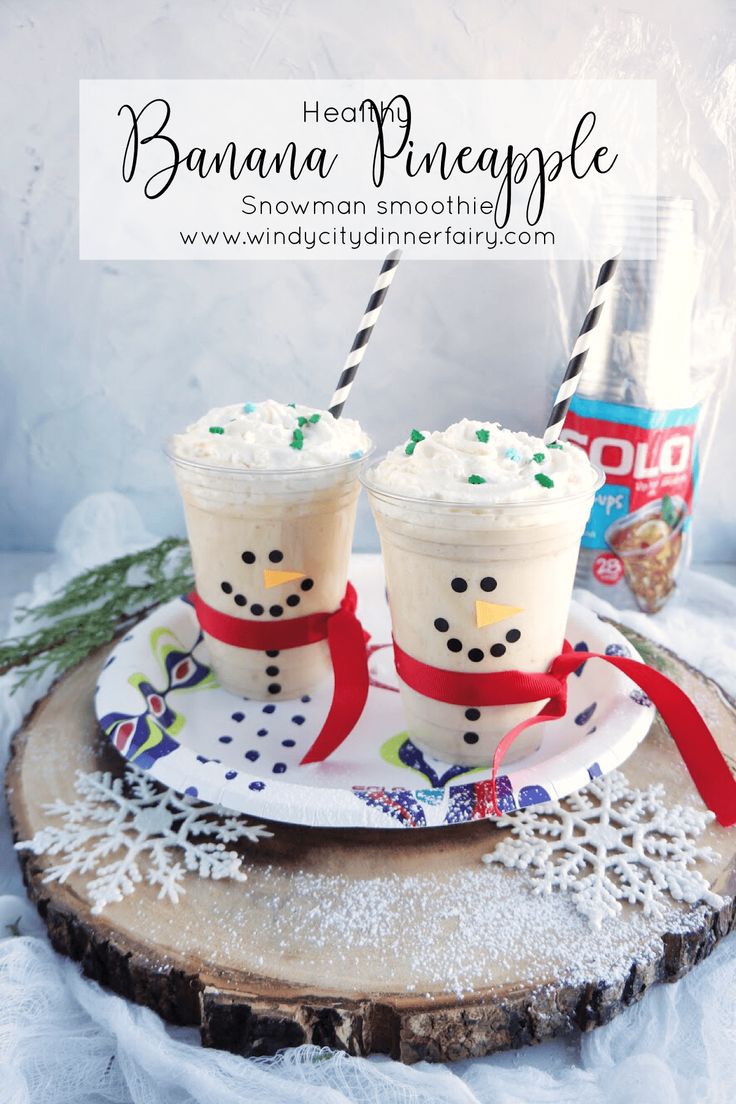 two glasses of banana pineapple drink on a plate with snowman decorations and candy canes