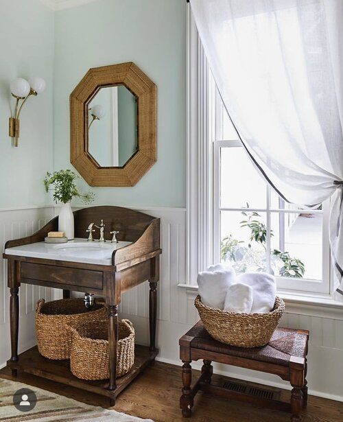 a bathroom with a sink, mirror and basket on the floor in front of it