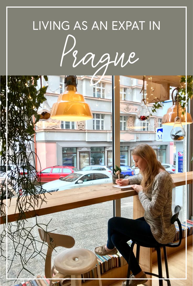 a woman sitting at a window looking out on the street and texting living as an expat in prague